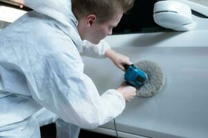 Auto mechanic use an electric polisher to polish the dried car paint. After passing the paint from the car painting room photo