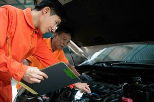 Both of auto mechanics are inspecting the engine of a customer's car being brought in for repair at a garage. photo