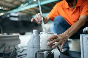 Auto mechanic in spray painting room mixing paint for use in spray painting a car that has undergone body repair photo