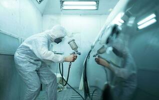 Auto mechanic in car spray room Use a spray nozzle Injected to the side of the car body with care to create beauty that blends with the original color of the car. photo