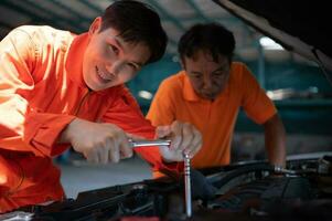 ambos de auto mecánica son inspeccionando el motor de un clientes coche siendo trajo en para reparar a un cochera. foto