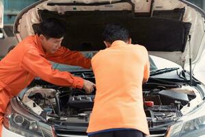 ambos de auto mecánica son inspeccionando el motor de un clientes coche siendo trajo en para reparar a un cochera. foto