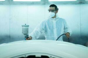 Auto mechanic in car spray room giving the spray nozzle injected into the car front bumper of the car with refinement in order to create beauty that blends with the original color of the car photo