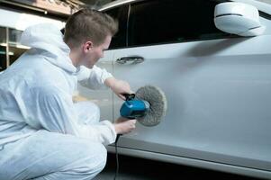 Auto mechanic use an electric polisher to polish the dried car paint. After passing the paint from the car painting room photo