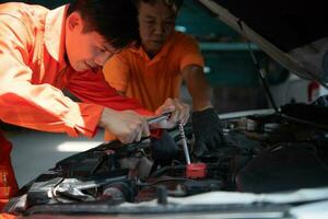 Both of auto mechanics are inspecting the engine of a customer's car being brought in for repair at a garage. photo