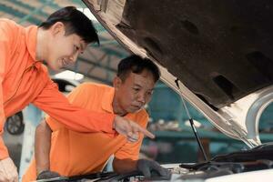 ambos de auto mecánica son inspeccionando el motor de un clientes coche siendo trajo en para reparar a un cochera. foto