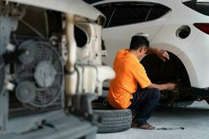 A auto mechanic checking the condition of a car's brake discs and the condition of the tires that have been used for a while photo