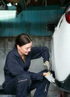 A female mechanic checking the condition of a car's brake discs and the condition of the tires that have been used for a while photo