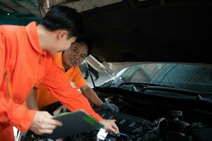 ambos de auto mecánica son inspeccionando el motor de un clientes coche siendo trajo en para reparar a un cochera. foto