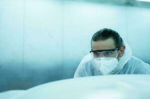 Auto mechanic in car spray room Inspecting the paint sprayed into the front bumper of the car that the pigment is complete, beautiful, harmonious with the original color of the car photo