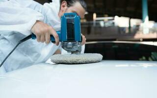 Auto mechanic use an electric polisher to polish the dried car paint. After passing the paint from the car painting room photo