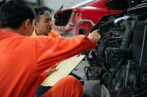 ambos de auto mecánica son inspeccionando el motor de un clientes coche siendo trajo en para reparar a un cochera. foto