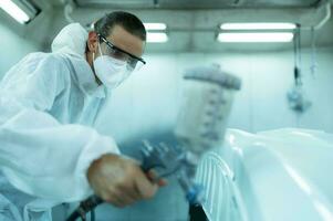 Auto mechanic in car spray room giving the spray nozzle injected into the car front bumper of the car with refinement in order to create beauty that blends with the original color of the car photo