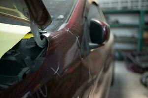 A car mechanic checks the condition of a car body to be repaired after a collision. by marking the X that need to be repaired photo