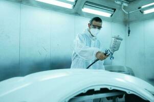 Auto mechanic in car spray room giving the spray nozzle injected into the car front bumper of the car with refinement in order to create beauty that blends with the original color of the car photo