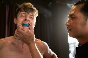 el Boxer debe vestir un diente collar antes de el lucha a evitar el riesgo de lesión desde dientes chocando cuando perforado en el barbilla o rostro, muay tailandés, tailandés marcial letras. foto
