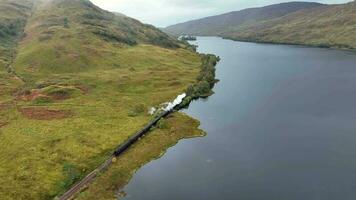 Steam Train in Scotland Passing By a Loch on the Famous Route video
