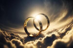 A pair of gold wedding rings floating in the sky. two wedding rings floating in the clouds with a sun in the background and a blue sky with clouds below them. . Wedding concept. photo