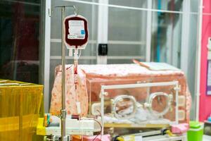 Sick newborn baby getting blood transfusion in a baby incubator in a hospital. photo