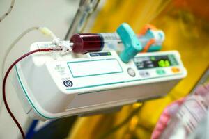 Blood in syringe pump machine transferring blood to a sick newborn baby in a hospital. photo