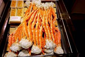 Closeup lots of burned king crab legs ready to serve for customer with labels price in the box at Kuromon market, Osaka, Japan. photo