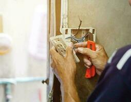 de cerca eléctrico reparar técnico participación un cortador cuchillo y fijación el eléctrico toma de corriente en antiguo edificio pared y borroso con Dom llamarada antecedentes. foto