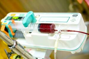 Blood in syringe pump machine transferring blood to a sick newborn baby in a hospital. photo