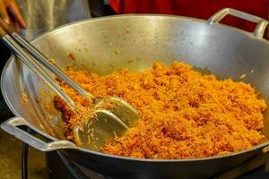 Chef hand holding flippers making MEE KROB in a big pan. MEE KROB is a popular snacks in Thailand that takes crispy fried rice noodles and tosses them with a tasty sweet sour sauce. photo