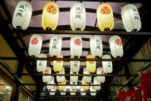 Perspective view of Japanese decorative paper lanterns hanging on ceiling of shopping market in Osaka, Japan. photo