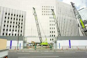 Hoisting crane tractors work and repairing building in downtown and on blue sky background. photo