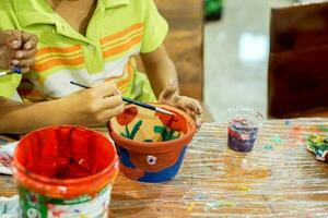 Child wear green polo shirt study and learning paint on flower pot in the art classroom. photo