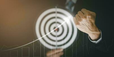 Targeting the business concept,businessman hand clenching himself with business goals and pointing arrow graph corporate future growth year on the black background,Leadership and Teamwork of business. photo