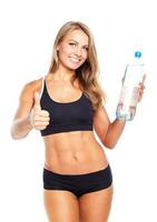 Young athletic girl with a finger up and bottle of water on white photo