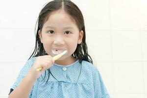 contento asiático linda niña cepillado dientes en baño foto