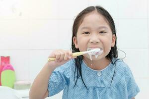 contento asiático linda niña cepillado dientes en baño foto