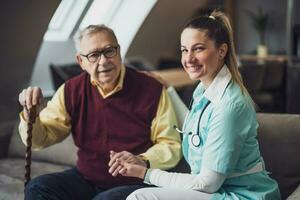 Elderly man with female caretaker at home. Health concept. photo