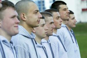 Many male faces in profile. A large group of young guys. Recruits. Build young soldiers. photo