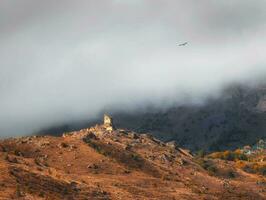 Beautiful dramatic landscape nature view in the mountains. Old Ossetian battle tower in the misty mountains. Digoria region. North Ossetia, Russia. photo