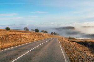 Empty morning highway through the pass in thick fog. Beautiful asphalt freeway, motorway, highway through of caucasian landscape mountains hills at cold weather in mid october. photo