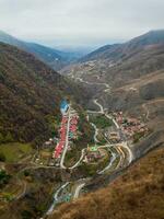 Small village in a gorge of high mountains. Erzi is a village in the Dzheyrakh district of Ingushetia. Vertical view of the village from a high autumn hill. photo