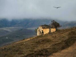 Old family crypt on a misty mountain slope. Old Erzi tower complex in the Jeyrah gorge, located on the extremity of the mountain range in Ingushetia, Russia. photo