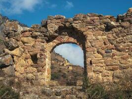 Old stone wall with arched passage. Old Egical towers complex, one of the largest medieval castle-type tower villages, located on the extremity of the mountain range in Ingushetia, Russia. photo