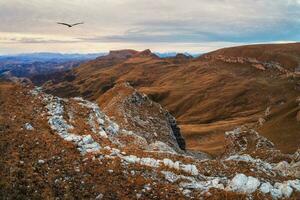 amanecer ver de bermamyt meseta rocas montañas en el borde de un acantilado en el distancia en dramático Mañana. atmosférico paisaje con siluetas de montañas. karachay-cherkesia, Cáucaso, Rusia. foto