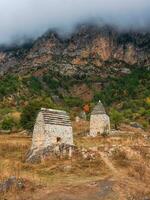 Majestic ancient tower buildings of Kelly and old family crypts in the Assinesky Gorge of mountainous Ingushetia, one of the medieval castle-type tower villages, located on the mountain range, Russia photo