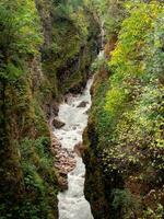 Digorskoe gorge and the Urukh River flows at breakneck speed at its bottom. Narrow gap in the mountains. Top view. photo