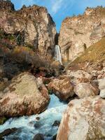 Amazing landscape view of big mountain waterfall known as Sultan, autumn grass, big stones and high rocks as a background. Caucasus nature, Jila Su Elbrus region, Kabardino-Balkaria. photo