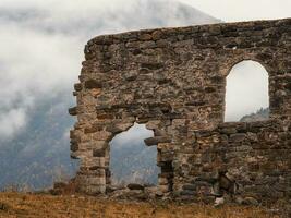 Old stone wall with arched passage. Old Egical towers complex, one of the largest medieval castle-type tower villages, located on the extremity of the mountain range in Ingushetia, Russia. photo