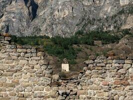 Old stone wall with arched passage. Old Pyaling towers complex, one of the largest medieval castle-type tower villages, located on the extremity of the mountain range in Ingushetia, Russia. photo