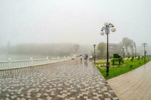 Beautiful wet and foggy embankment with people walking under umb photo