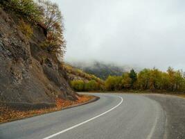 Turn on the misty asphalt mountain highway. Asphalt road through the hills and mountains. Turn on an empty mountain road. Old cracked asphalt mountain road in Ingushetia. photo